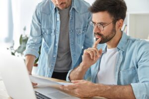 two-successful-stylish-man-financiers-analyze-business-documents-work-new-startup-project_273609-16593